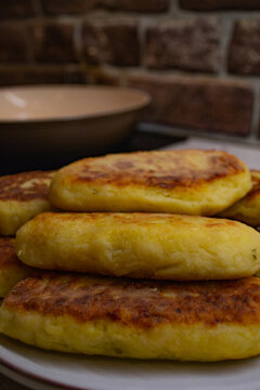 Frying potato zrazy with cabbage filling in a pan on an induction stove. Crispy golden fried patties served on a plate, showcasing the final step of cooking traditional Eastern European rustic comfort