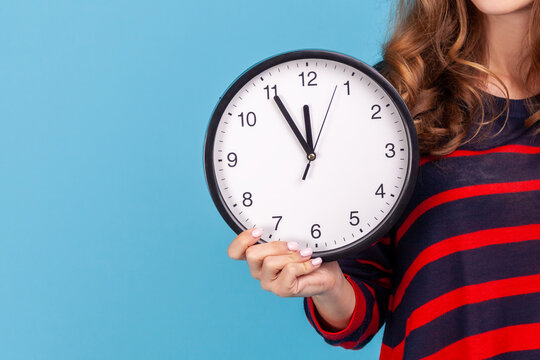 Anonymous user holding alarm clock to show deadline pressure or time management concept for busy workers isolated over blue background with copy space