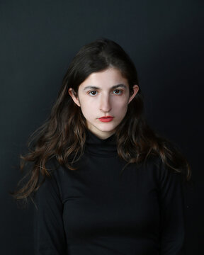 Junge Frau im dunklen Rollkragenpullover vor schwarzem Hintergrund &ndash; ruhiges Fine-Art-Portr&auml;t mit melancholischer Stimmung und minimalistischer &Auml;sthetik. Viel copyspace und copy space.