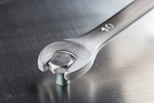 wrench tightens bolt in metal aluminum plate. Industrial mechanical workshop. Metalworking and locksmithing.