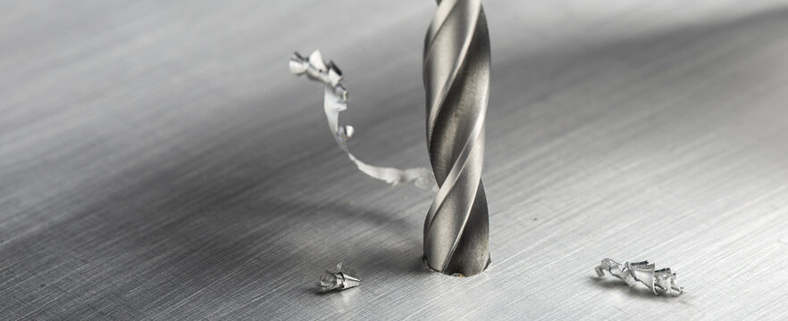 drill bit make hole in metal aluminum plate with chip. Locksmith work. Industry of construction.