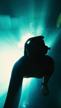 Vertical Underwater Video of Man Free Diving in Cenote Near Puerto Morelos With Sun Beams Through Water