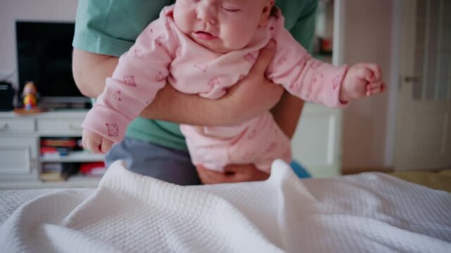 Close up of a baby being gently supported during tummy time on a padded table