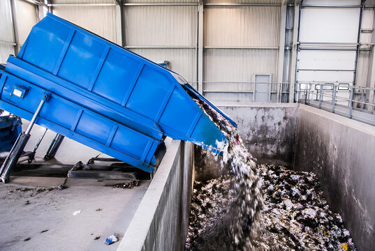 Sustainable waste management facility in action, with an industrial compactor efficiently emptying discarded materials for modern recycling success