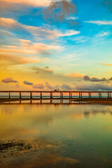Fototapeta premium A tropical beach scene at sunset featuring a soft gradient sky of blue, yellow, and orange hues