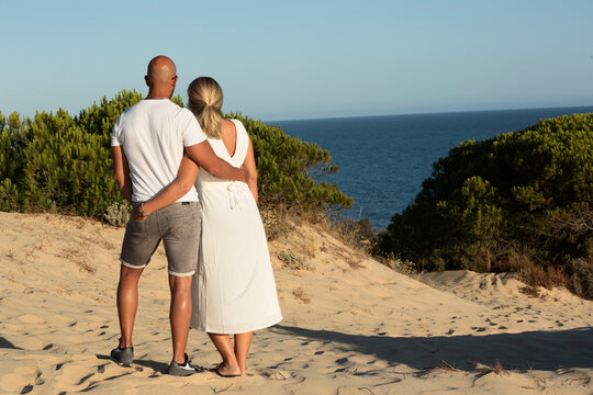 Pareja abrazada mirando el mar.