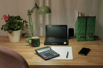 Fototapeta premium Remote workplace of accountant, bookkeeper. No people. Work place in a kitchen. Working from home. Business report, data entry for company tasks. Laptop, calculator and paperwork. Study, productivity