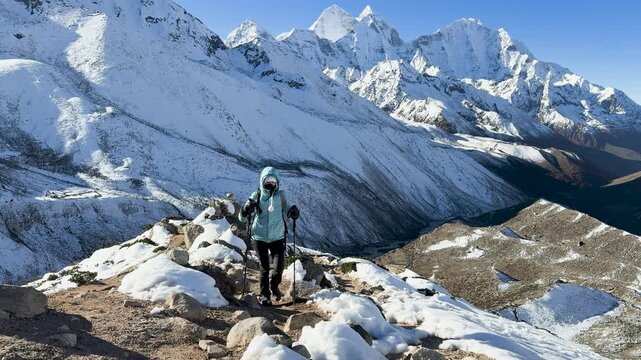 Hiker ascending rocky trail above Himalayan valley in Nepal