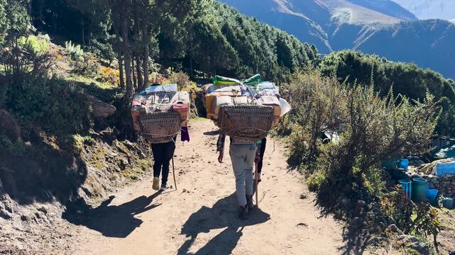 Sherpa porters carrying cargo on Himalayan trail in Nepal