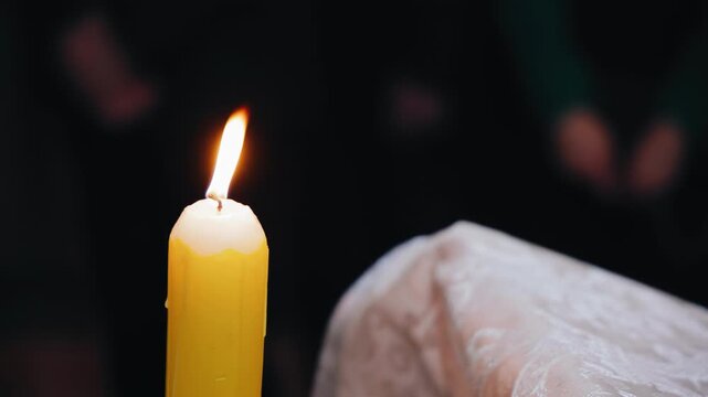 A close-up of a burning candle in a temple. The flame illuminates everything with a soft light