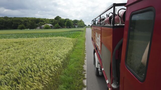 Red fire truck driving past rural fields and farmhouses