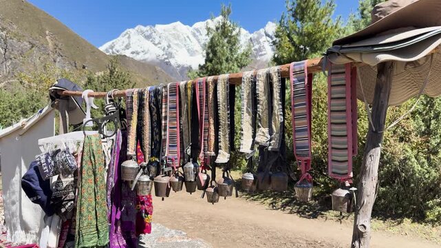 Yak bells and textiles hanging before Himalayan peaks in Nepal
