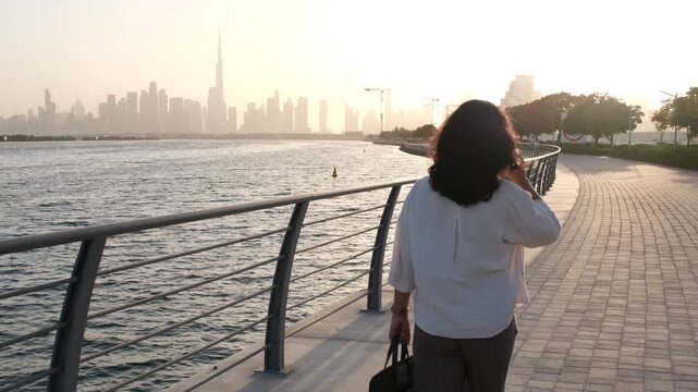 Female startup founder working remotely outdoors with laptop and Dubai skyline video