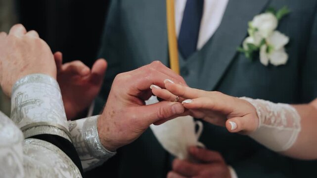 An Orthodox priest puts wedding rings on the hands of the newlyweds. Close-up shooting