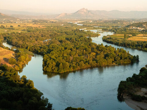 High angle view of a winding river valley and distant mountains during golden hour. Captured from the historic Rozafa Castle in Shkoder, Albania.