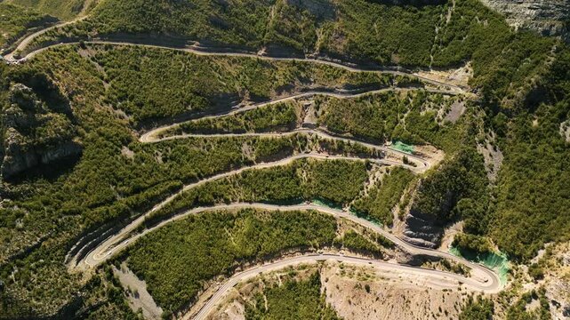 Cinematic aerial drone view of the famous SH20 mountain pass in Albania. Steep serpentines and switchbacks carved into the rocky landscape.
