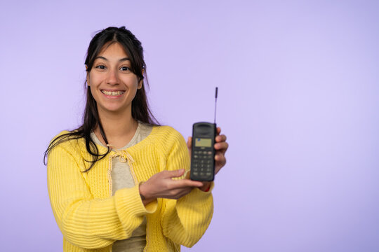 Young woman holding vintage 90s mobile phone