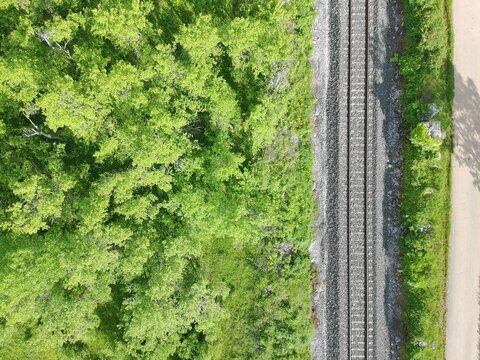 Aerial drone view of railway tracks running through green forest landscape