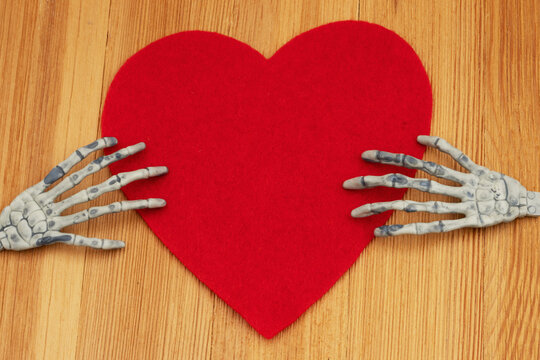 Blank red heart with two skeleton hands on a wood desk
