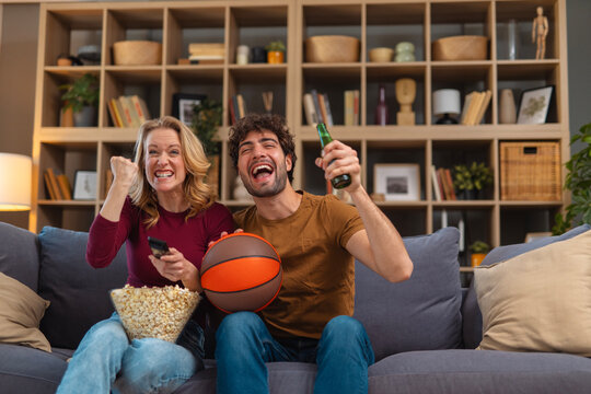 Couple cheering basketball game while watching tv at home