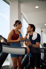 Fototapeta premium Happy sports couple talking during water break in health club.