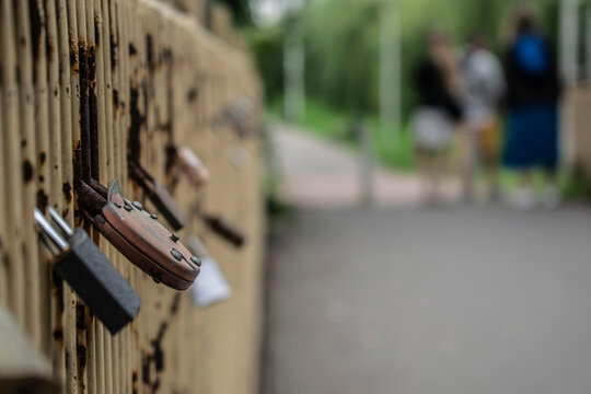 Love locks attached to metal bridge fence with blurred people background 2020.07.12 - Kazimierza Wielka, Poland