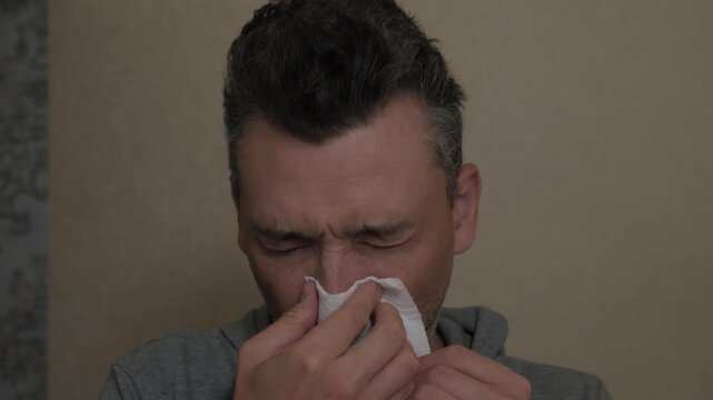 Closeup of sick man. Man showing signs of illness up close. Close examination of fatigued man with cold symptoms. Detailed depiction of unwell man with watery eyes and nasal congestion at home