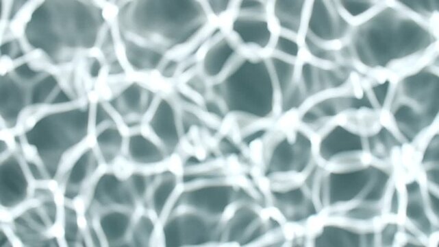Multiple waves of water cross each other and reflections sunlight in slow motion. Shadow effect. Ripples spontaneously on blue background. Beauty shot for skin care cosmetics advertisement. 4k 