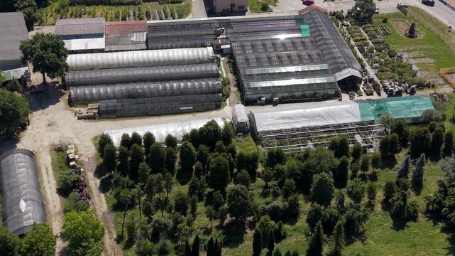 Aerial View of a Greenhouse Facility: An expansive greenhouse complex with multiple structures and surrounding trees, offering a bird's-eye perspective of horticultural operations.