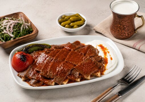 Turkish Iskender Meal Arrangement with Side Dishes on Light Background