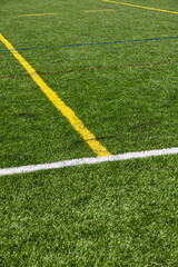 Obraz premium Close-up of an artificial turf sports field with marked lines crossing on synthetic grass. Outdoor sports surface suitable for football, soccer, training, and recreational activities.