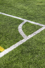 Fototapeta premium Close-up of an artificial turf sports field with marked lines crossing on synthetic grass. Outdoor sports surface suitable for football, soccer, training, and recreational activities.