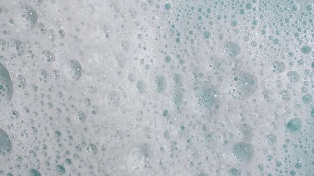 Bubbles of white soap foam on a blue background. Bathtup Soap Foam. Texture of Soap Foam Bubbles. Natural White Shampoo Bubbles Motion. . High quality 4k footage
