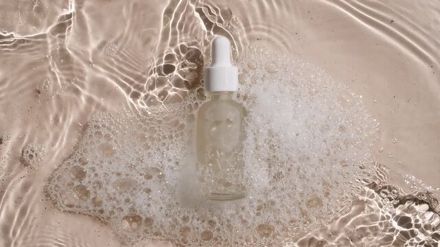 Bottle with a pipette for collagen serum, oil, toner on water texture background surface with bubbles of white soapy foam. Medical skin care. Packaging for design, advertising of a cosmetic product.4k