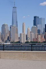 Obraz premium Vertical Scene Capturing Manhattan Skyscrapers Near River With Protective Railing new york
