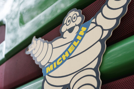 Dusseldorf, Germany - October 26 2025: Michelin mascot badge mounted on a green truck grille with red mesh background
