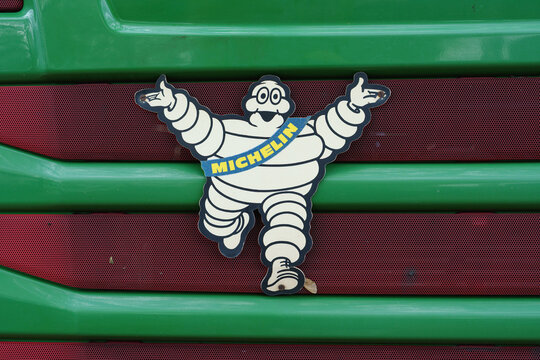 Dusseldorf, Germany - October 26 2025: Michelin mascot badge mounted on a green truck grille with red mesh background