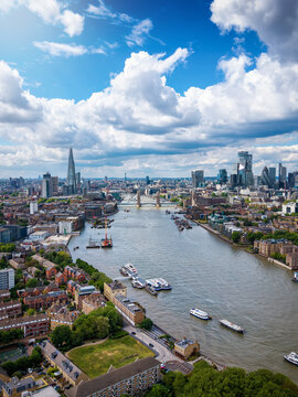 Aerial view of the cityscape of London, England, with City, Tower Bridge and River Thames during a sunny summer day with cloudscape