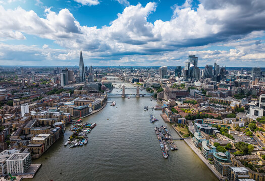 Aerial view of the cityscape of London, England, with City, Tower Bridge and River Thames during a sunny summer day with cloudscape