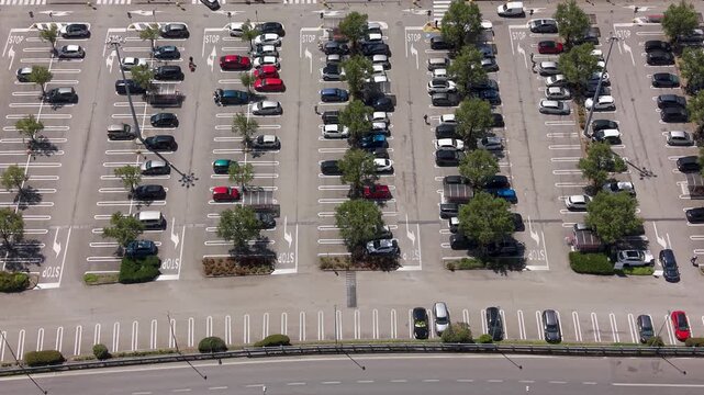 Parking Lot Panorama: An aerial view captures a meticulously organized parking lot filled with numerous cars, interspersed with trees and marked parking spaces.