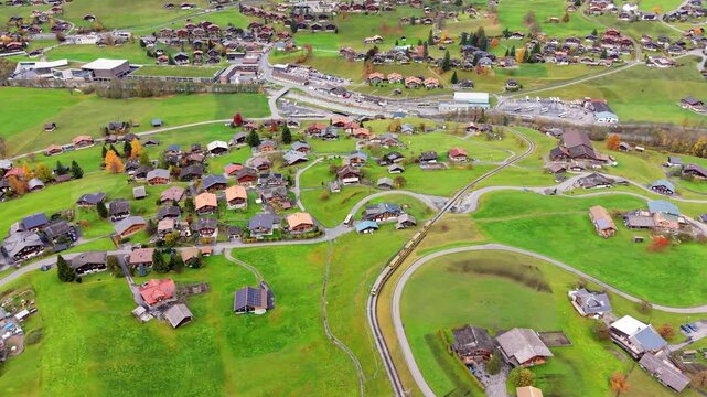 Aerial view of Grindelwald town center, surrounding residential areas, and the train line in autumn. Canton of Bern, Switzerland.