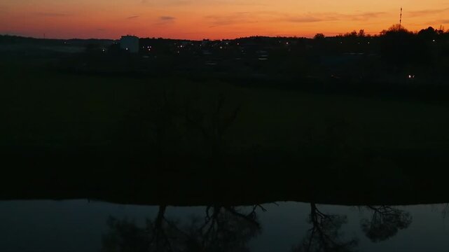 Brigh gold spring sunset over the river with reflections in the water. Calm nature scenic from the hill