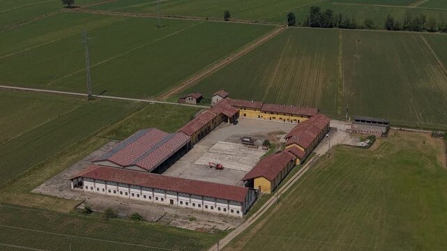 Rural Farmstead Aerial View: An expansive aerial perspective captures a traditional farm complex nestled amidst cultivated agricultural fields under a clear sky.