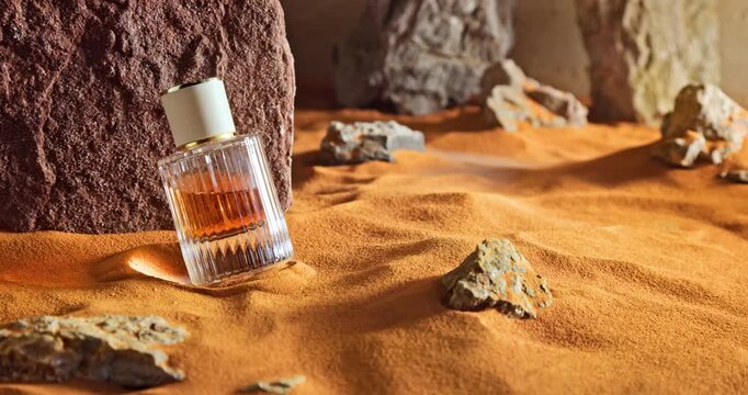 Amber perfumes in translucent glass bottle on sand.