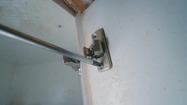 Rusty Broken Cabinet Door Hinge Being Removed by Hand | Close-Up Parallax View | Kitchen Furniture Repair and DIY Home Maintenance Concept