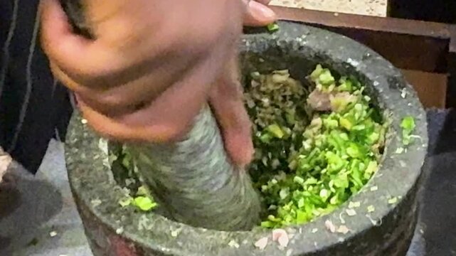 Closeup of Grinding Chilis with a Mortar and Pestle to Make Thai Green Curry Paste