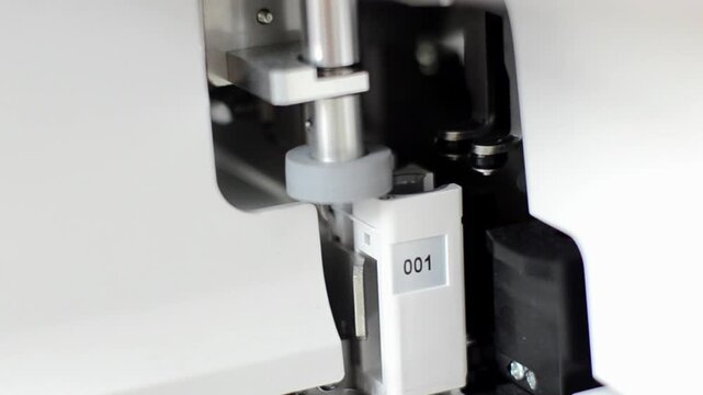 Close up of a precise laboratory automated sampling machine nozzle needle mechanism inside medical diagnostic equipment