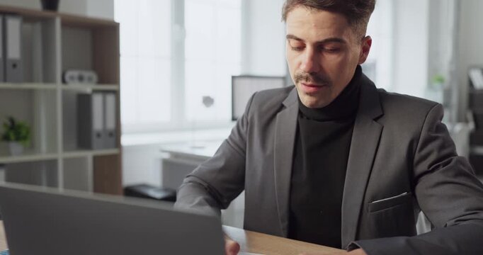 Man businessman in office on video chat call. Focused professional attends online meeting on laptop to discuss strategy and ensure strong remote teamwork. Concept of remote business teamwork.
