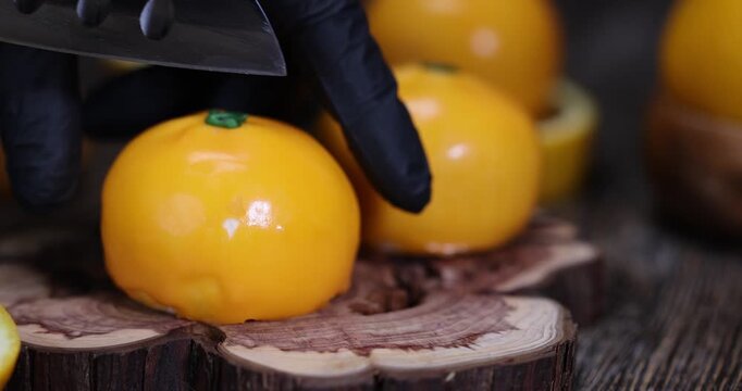 a pastry with glossy glaze, a round pastry with imitation fruit peel and juicy flesh in the foreground with an authentic look and clear detailing of decorative elements.
