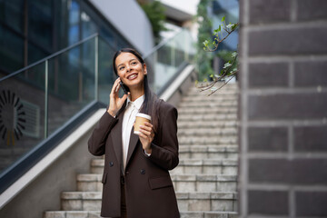 Fototapeta premium Professional woman talking on phone holding coffee